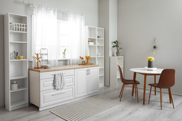 Interior of light kitchen with dining table and shelving unit