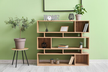 Fototapeta na wymiar Wooden bookshelf and chair with houseplant near color wall