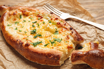 Tasty Ajarian khachapuri on parchment background, closeup