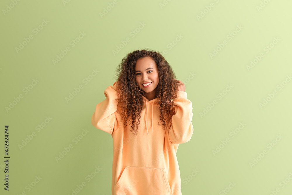 Wall mural beautiful young african-american woman in stylish hoodie on color background