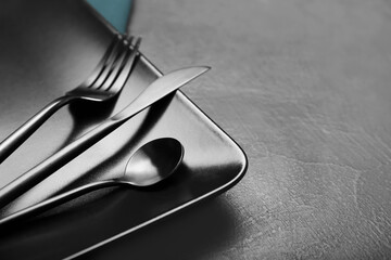 Stylish cutlery with black plate on dark background
