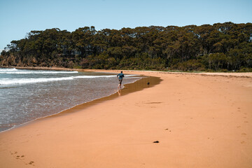 Man and little dog running on beach