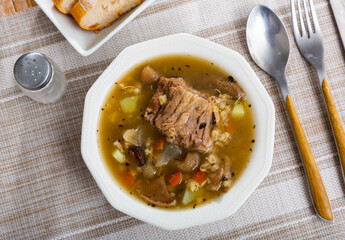 Delicious thick rustic style pearl barley mushroom soup with pork meat and vegetables..