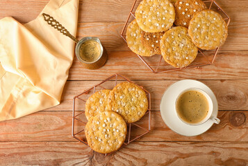 Grids with delicious chocolate cookies and cup of coffee on wooden background