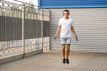 Sporty young man jumping rope outdoors