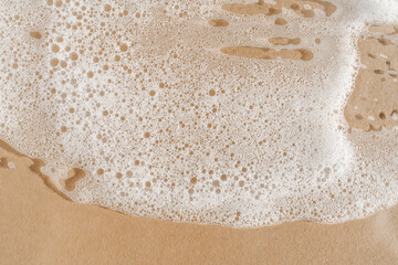 Texture of white foam on a beige background.