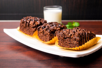 Chocolate Brownies with a glass of milk on white plate and wooden table