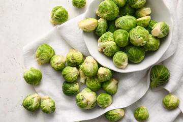 Bowl with fresh ripe Brussels cabbage on light background