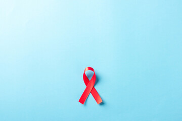 Red bow ribbon symbol HIV, AIDS cancer awareness with shadows, studio shot isolated on blue background, Healthcare medicine concept, World AIDS Day
