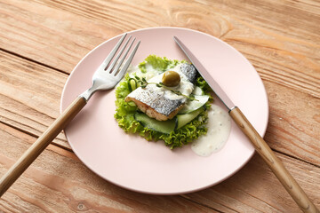 Plate of tasty sea bass fish with vegetables on wooden background
