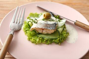Plate of tasty sea bass fish with vegetables on wooden background