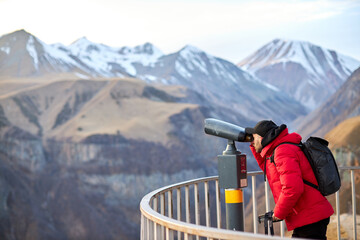 Hipster young man with black backpack looking on observation deck, tourist traveler on background panoramic view of the city, coin operated binoculars. Mock up for text message