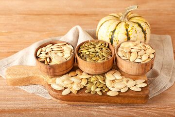 Bowls with natural pumpkin seeds on wooden background