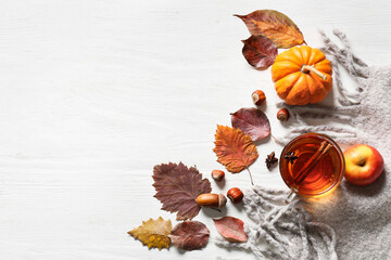 Fototapeta na wymiar Composition with cup of tea, autumn leaves and scarf on light wooden background