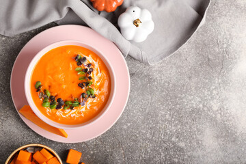 Bowl with tasty pumpkin cream soup on grey background