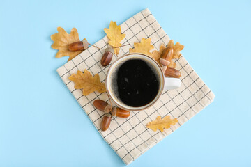 Cup of coffee with acorns and autumn leaves on blue background