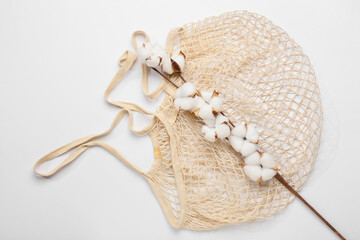 Cotton flowers and shopping bag on white background