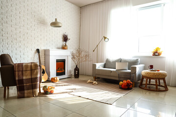 Cozy interior of living room with fireplace, sofa and autumn decor