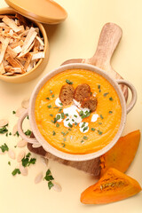 Pot with delicious pumpkin cream soup and pita on color background