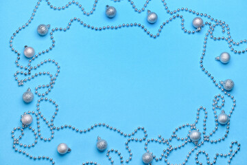 Frame made of Christmas balls and beads on color background
