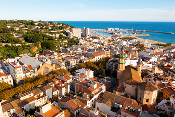 Picturesque aerial view of Arenys de Mar cityscape on Mediterranean coast overlooking parish church on sunny autumn day, Comarca Maresme, Catalonia, Spain
