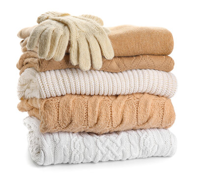 Different stylish sweaters and gloves on white background
