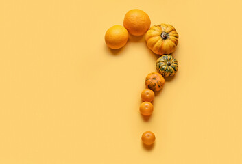 Question mark made of pumpkins on color background