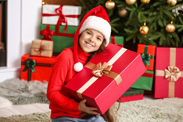 Fototapeta na wymiar Cute little girl with gift at home on Christmas eve