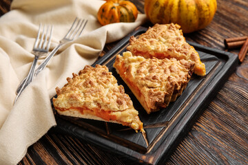 Board with pieces of tasty pumpkin pie on wooden background