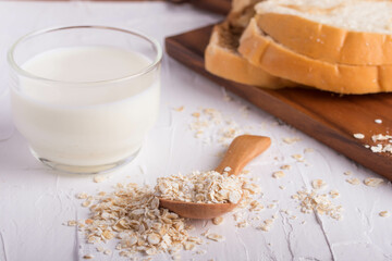 oatmeal in wooden spoon and fresh milk on white background healthy food