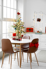 Dining table with food in interior of light kitchen decorated for Christmas