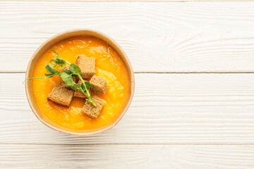 Bowl of tasty pumpkin cream soup on white wooden background