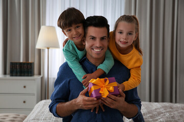 Man receiving gift for Father's Day from his children at home