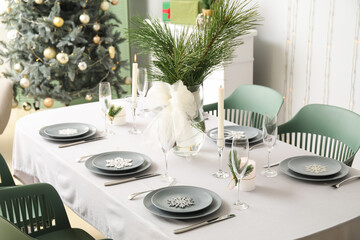 Dining table with beautiful setting for Christmas celebration in festive room