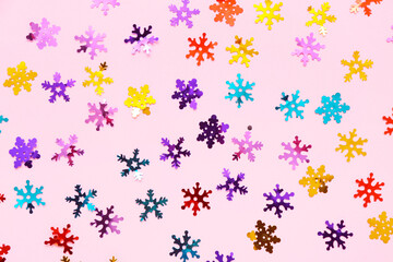 Colorful confetti in shape of snowflakes on pink background