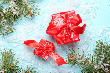 Composition with Christmas gifts, fir branches and snow on blue background