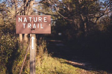 Wooden sign marking trail name on a wooden post. Arrow marking which direction the trail goes. Sun...
