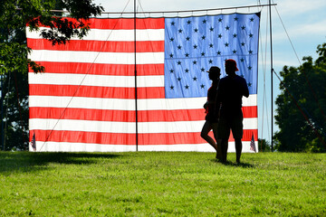 silhouette of a young couple and a huge US National flag at National Mall during Memorial Day...