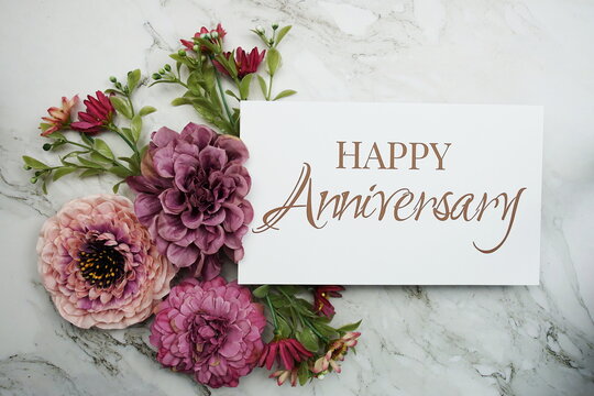 Happy Anniversary with pink flower bouquet on marble background
