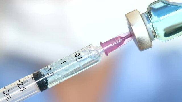doctor's hand holds a syringe and a blue vaccine bottle at the hospital. Health and medical concepts.