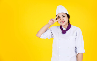 Portrait studio shot of Asian professional successful smart confident hotel restaurant female executive chef in white cooking uniform standing smiling look at camera crossed arms on yellow background