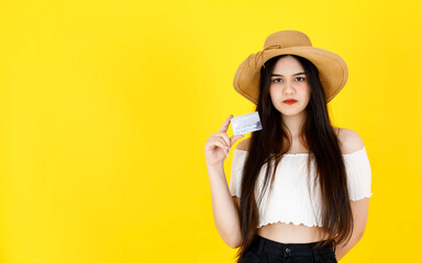 Portrait studio shot of Asian young beautiful sexy long black hair female teenager model wearing crop top outfit and hat standing holding shopping online credit card in hands on yellow background