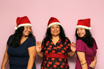 Body positive overweight Latina mom and daughters wearing Santa hats are happy and excited about the arrival of December and celebrating Christmas as a family
