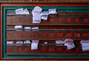 Chinese fortune telling paper strips in wooden shelves a row along with red numbers at Chinese shrine. No focus, specifically.