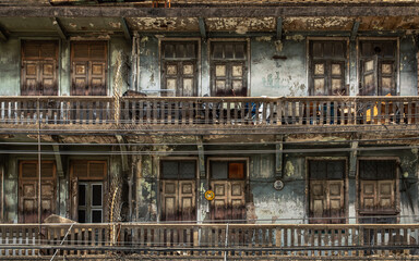 External of old building with wooden windows and wooden door on balconies was left to deteriorate...