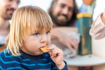 boy eating a cookie with his family in blurry background