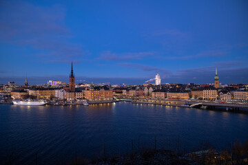 Beautiful panorama of Stockholm at night with sea, buildings, boats and night city lights. Capital of Sweden photographed from the hill. 