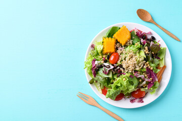 Fresh organic vegetables with quinoa salad on plate with wooden fork and spoon ready to eating on color background, Healthy Vegan food, Top view