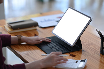 Close up view businesswoman working with computer tablet and using calculator.