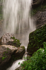 A close-up of the waterfall with rock and small green trees in natural light from Thailand.